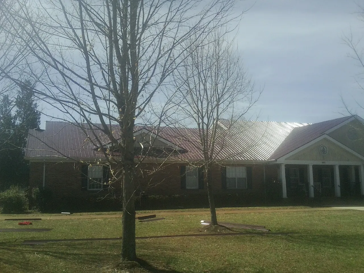 Red metal roof on a brick building seen from the front lawn in Mallory