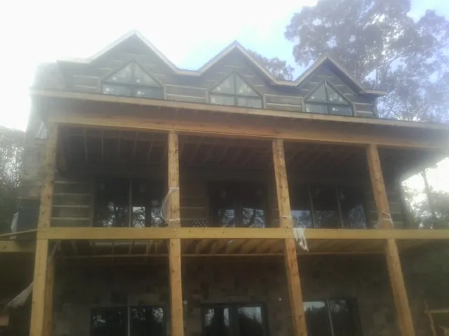 Dormers and porch framing on a large log home under construction — Roof Coating work by our crew in Mallory