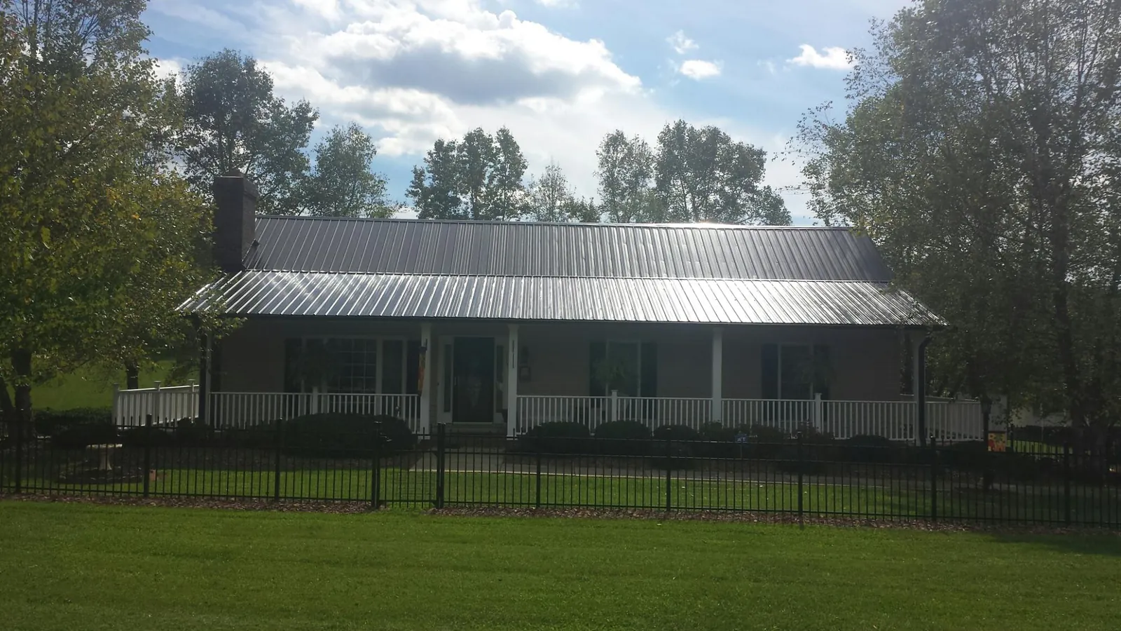 Gray metal roof on a brick ranch with a full width front porch — Gutter Guard Installation work by our crew in Mallory