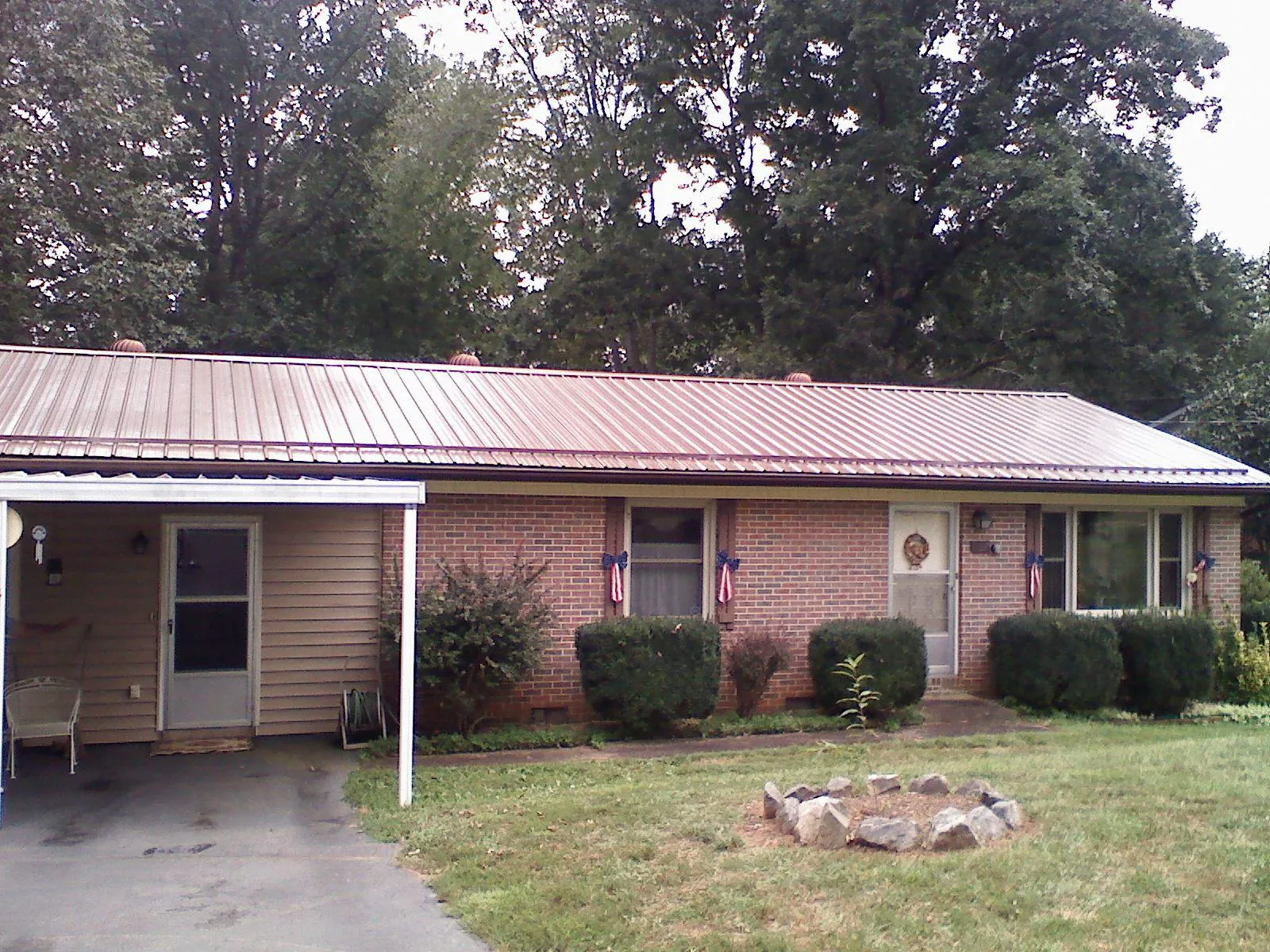 Bronze metal roof and carport on a brick ranch home — Roof Repair work by our crew in Mallory