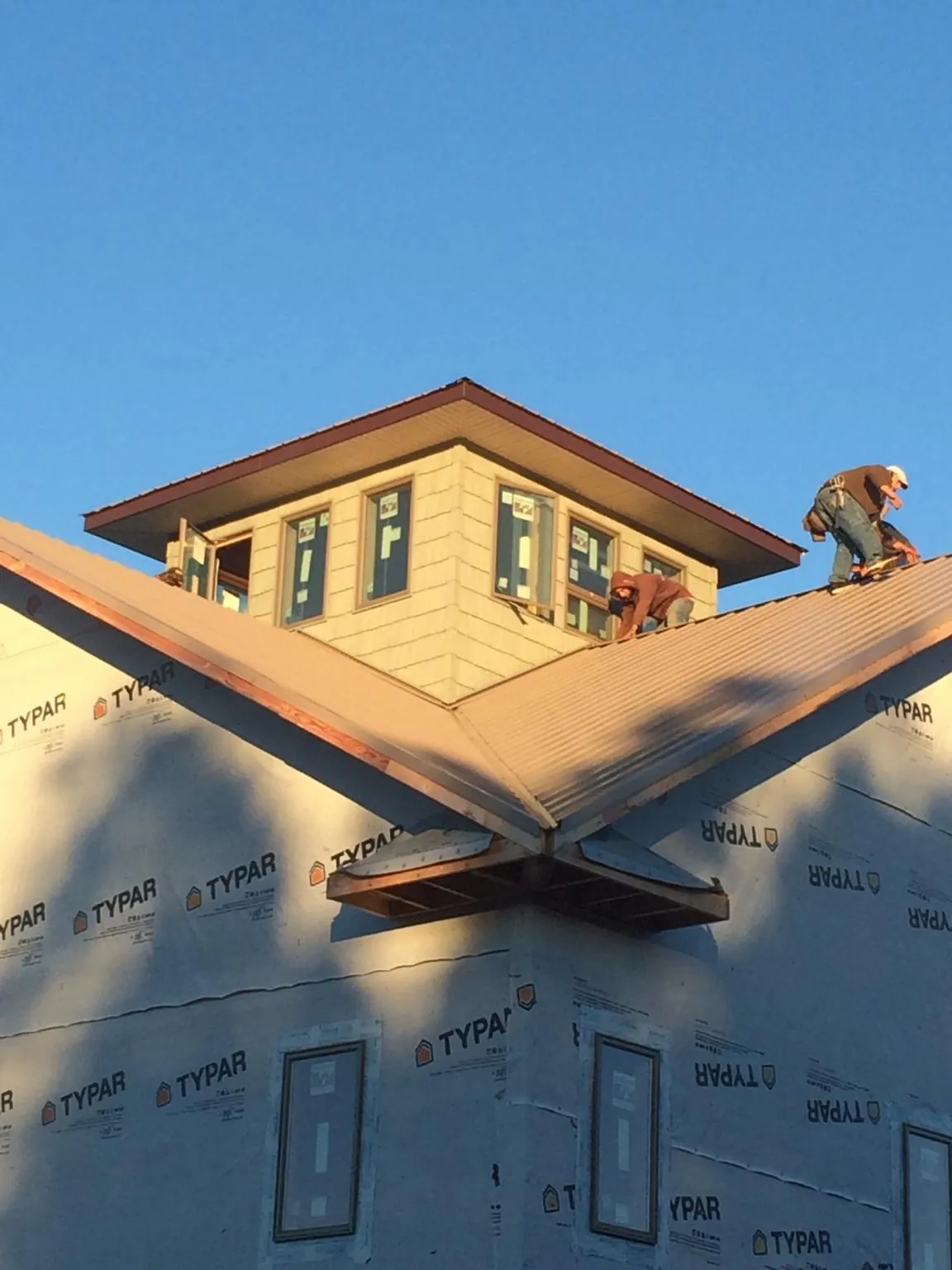 Roofers working around a rooftop cupola on a new metal roof at sunset — Roof Waterproofing in Mallory by Roofing Brothers